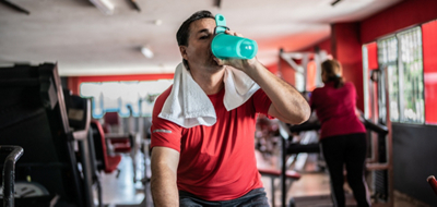 Man drinking from his shaker bottle on an exercise bike